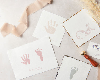 A photography showing a collection of Atria UK's keepsakes all on handmade paper. The keepsakes shown are a child's handprint keepsake, a baby scan keepsake, a baby's footprint keepsake and a hand and footprint pair keepsake where both a hand a foot print are side-by-side on the same print.