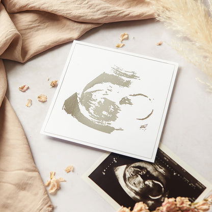 A Silver foil and white cardstock baby scan keepsake gift, photographed alongside the original hospital issued 12 week baby scan. A paper keepsake to cherish and the perfect gift for parents-to-be.
